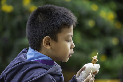 Side view of boy eating food at outdoors