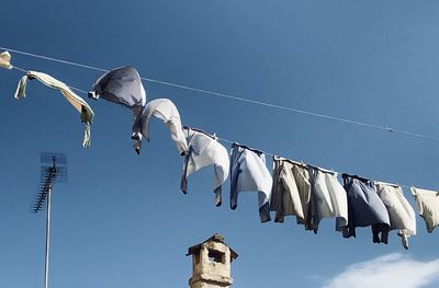 Low angle view of clothes drying against blue sky