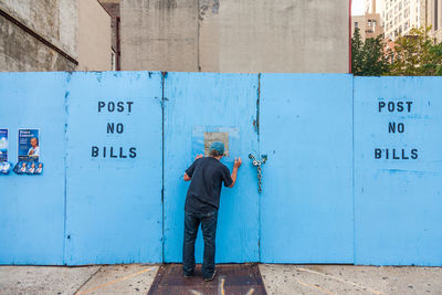 Man standing by text on wall