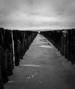 Empty footpath amidst road against sky