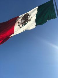 Low angle view of flag against blue sky