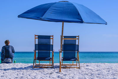 Deck chairs on beach against blue sky