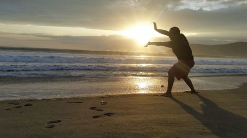 Full length of man on beach against sky during sunset