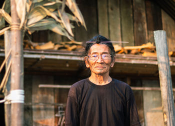 Senior man standing against hut