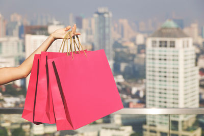 Female hand holding three pink shopping bags