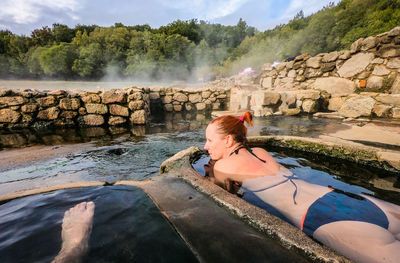 Woman wearing bikini while lying in hot spring