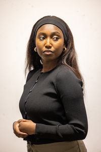 Portrait of young woman standing against wall