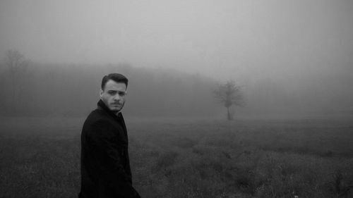 Woman standing on field in foggy weather