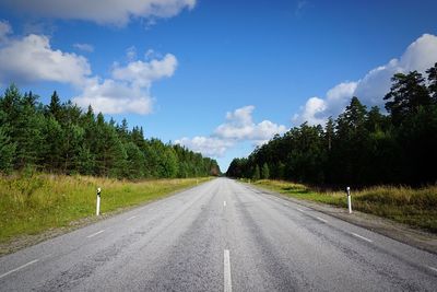 Surface level of road by trees against sky