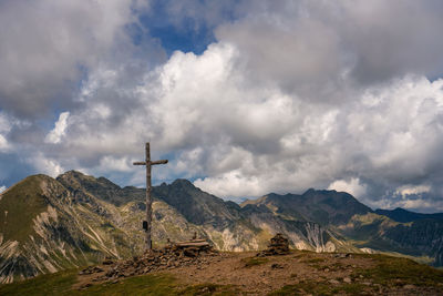 Wooden cross on mountain against sky
