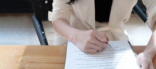 Midsection of man holding paper with text on table