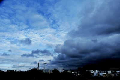 Low angle view of silhouette trees against blue sky