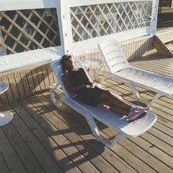 Young woman reclining on lounge chair at deck