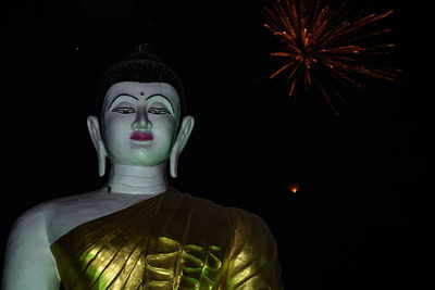 Low angle view of illuminated statue against black background