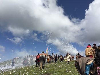 People standing on field against cloudy sky