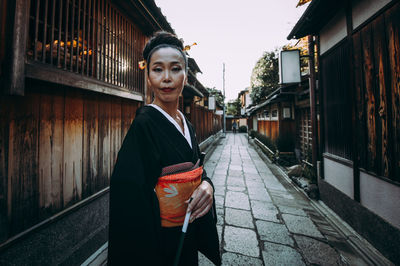 Portrait of woman standing on footpath in city