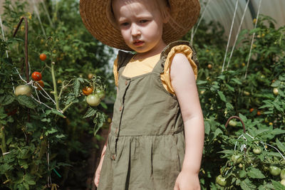 Girl wearing hat standing against plants