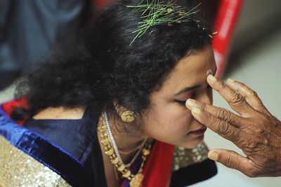 Cropped hand applying tilaka on woman forehead