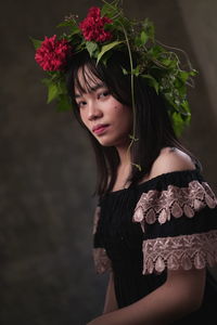 Portrait of beautiful young woman standing by flowering plant