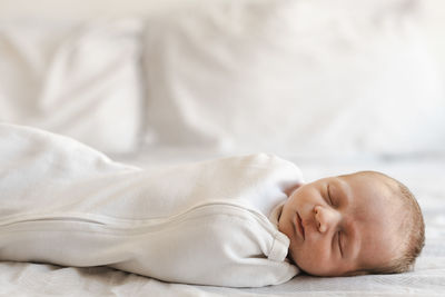 Low section of newborn sleeping on bed