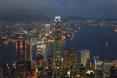 Illuminated modern buildings in city against sky at night