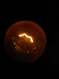 Close-up of illuminated light bulb against black background
