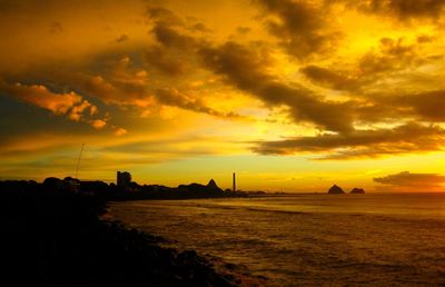 Scenic view of sea against dramatic sky during sunset