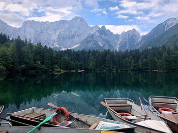 Scenic view of lake and mountains against sky with boats 