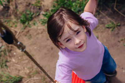 Portrait of a happy smiling child sitting on a swing on a sunny day