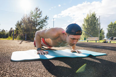 Sportsman practicing push-ups on exercise mat at park