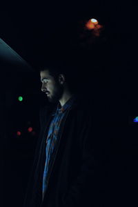 Side view of young man looking away at night