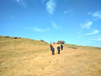 Rear view of men walking on mountain against sky