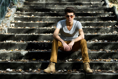 Full length of confident handsome man sitting on steps