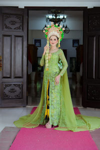 Portrait of young woman standing against wall