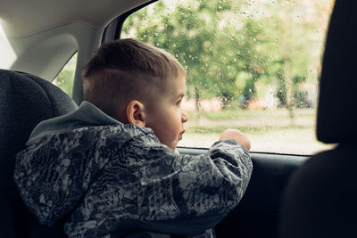 Little boy looking through window of car
