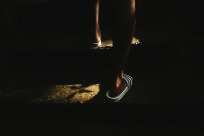 Low section of man standing against black background