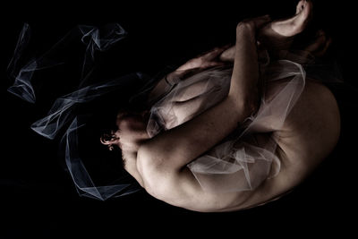 Young woman lying down against black background