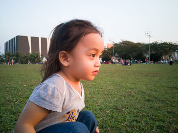 Close-up of girl looking away sitting on grass at park