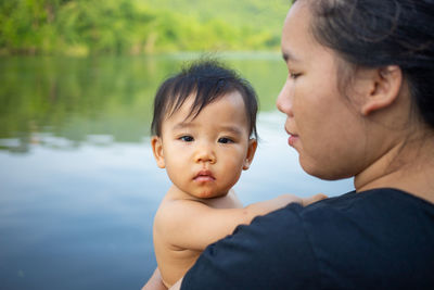 Portrait of baby with mother by lake 