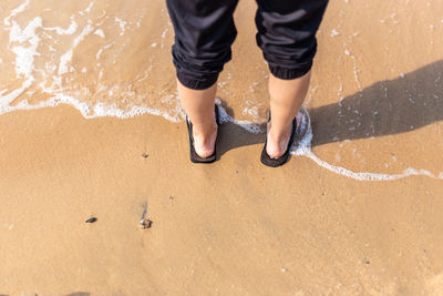 Low section of man standing on beach