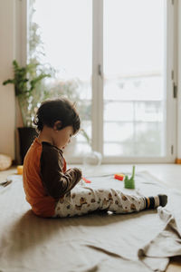 Side view of boy lying on bed at home