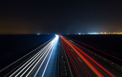 Light trails on bridge against sky at night