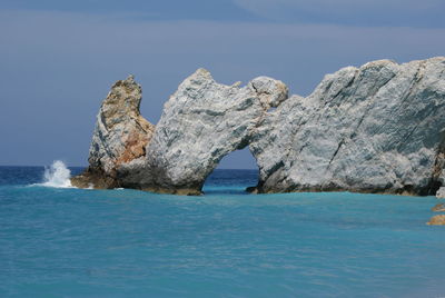 Natural arch on sea against sky