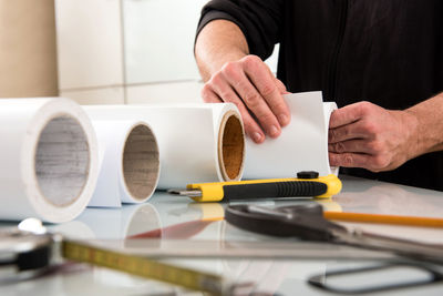 Cropped image of person rolling paper on table