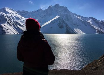 Rear view of woman with lake in background against snowcapped mountains