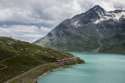 Aerial view of train on railroad track by lake against mountain range