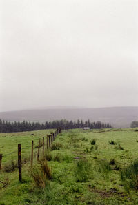 Wooden fence on field against sky