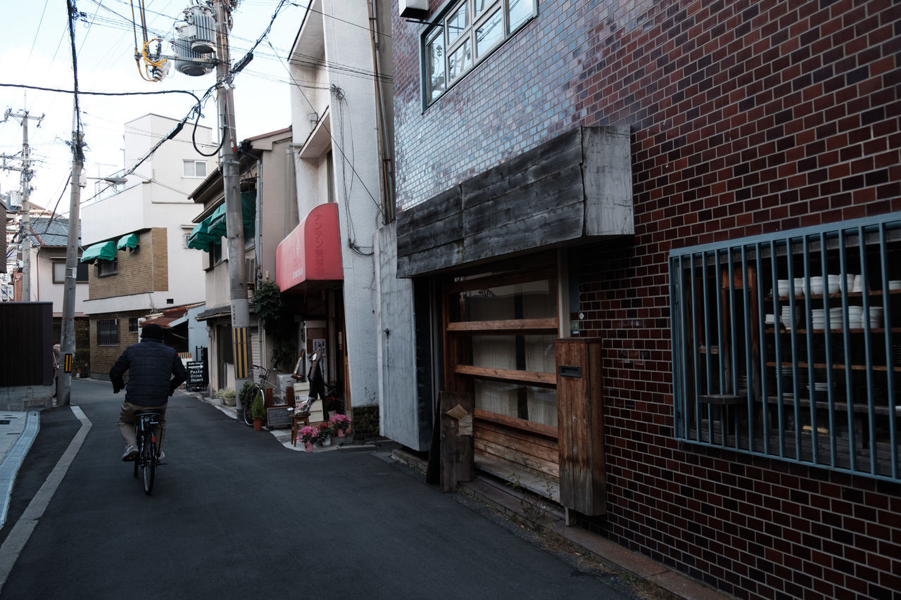 MAN WALKING ON COBBLESTONE STREET