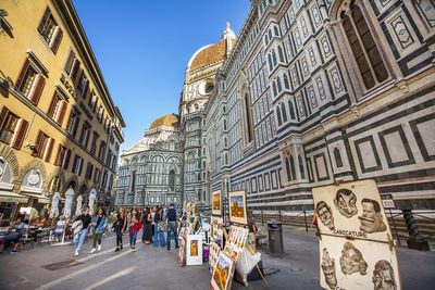 People walking on street amidst buildings in city