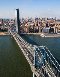 High angle view of manhattan bridge over river by buildings against sky